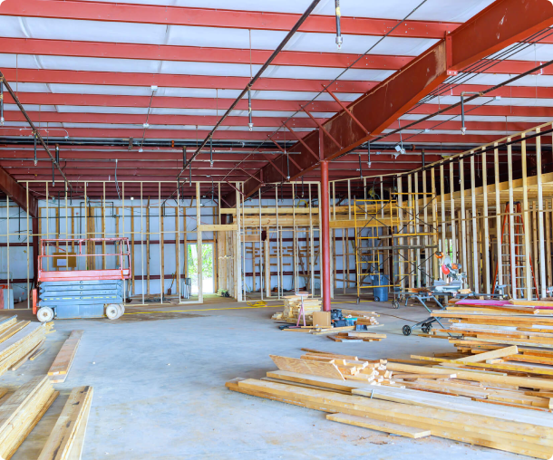 Interior view of a building under construction with steel beams and wooden framing.